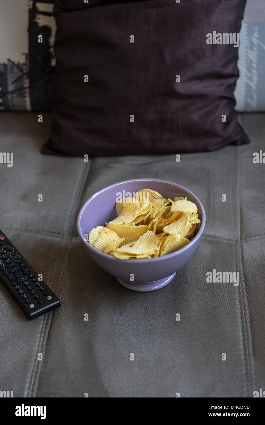 Chips und Fernbedienung vom TV auf einem Sofa, in der Nähe Stockfoto