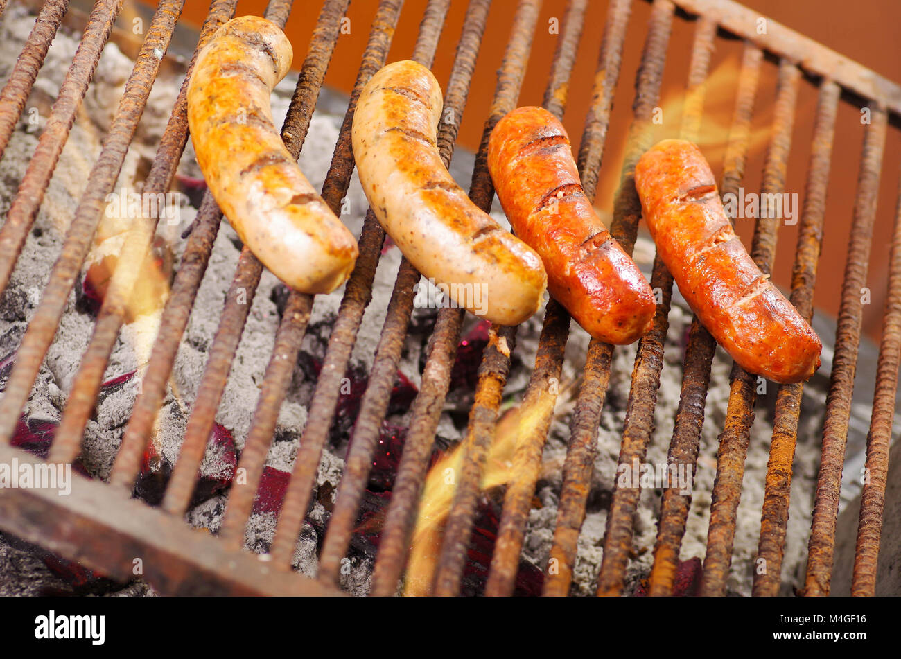 Blick von oben auf die vier grillen Würstchen auf Grill, Kohle feuerte