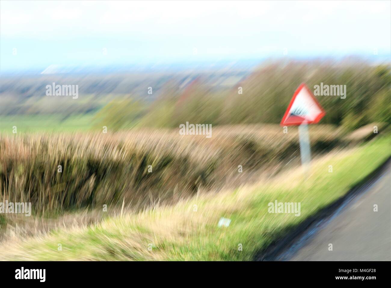 Verschwommenes Bild der Straße mit 10% Steigung Warnschild in Oxfordshire, UK Stockfoto