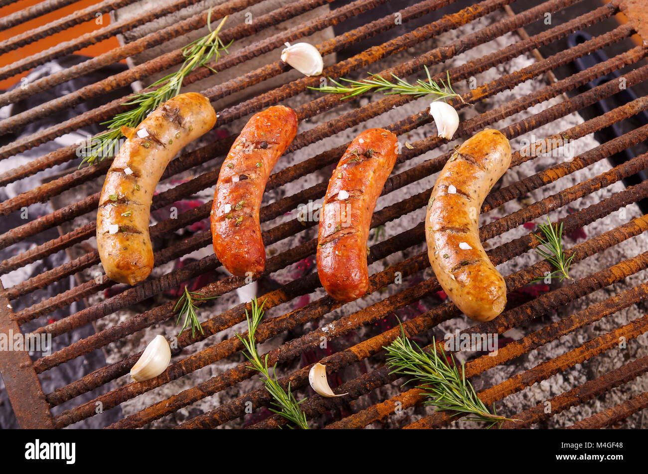 Blick von oben auf die vier grillen Würstchen auf Grill mit einigen