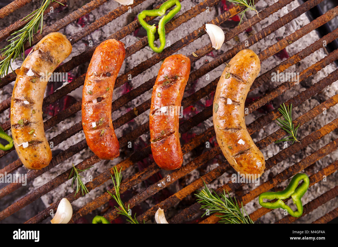 Blick von oben auf die vier grillen Würstchen auf Grill mit einigen