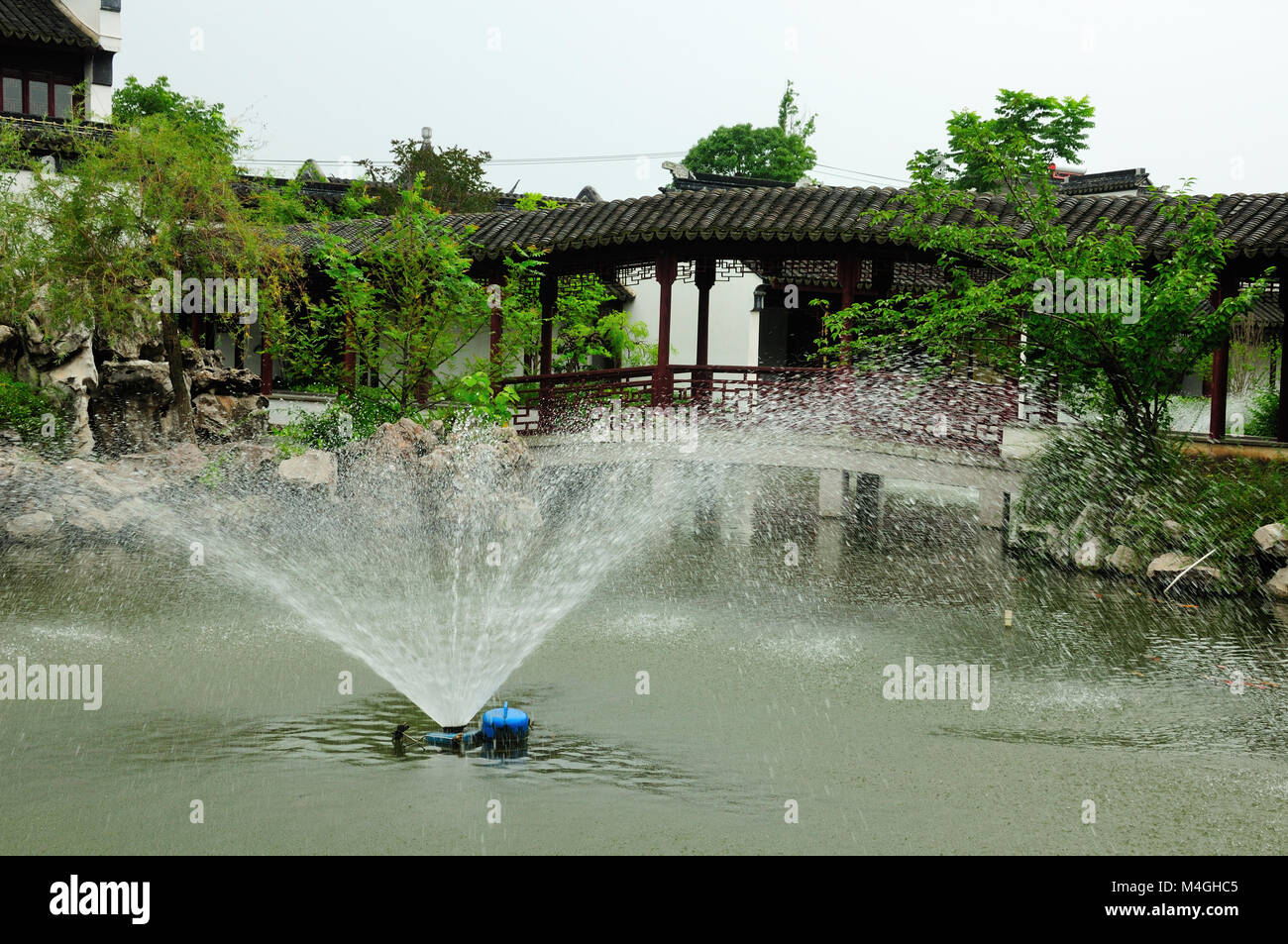 Ein Brunnen und überdachten Korridor an der klassischen chinesischen Li Yuan Garten in Zhaojialou in Shanghai China an einem bewölkten Tag. Stockfoto