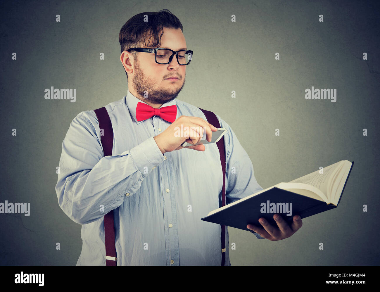 Intelligenter Mann in Brillen Holding und unter Foto von wertvollen Informationen mit Smartphone. Stockfoto