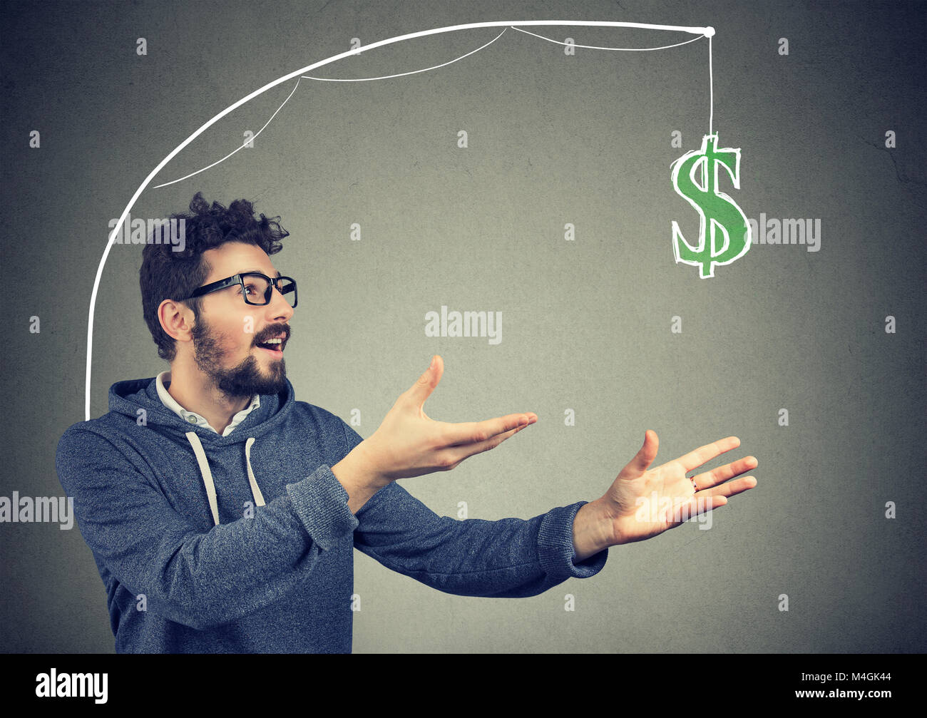 Gierig junger Mann jagt Dollarschein Geld auf grauem Hintergrund. Stockfoto