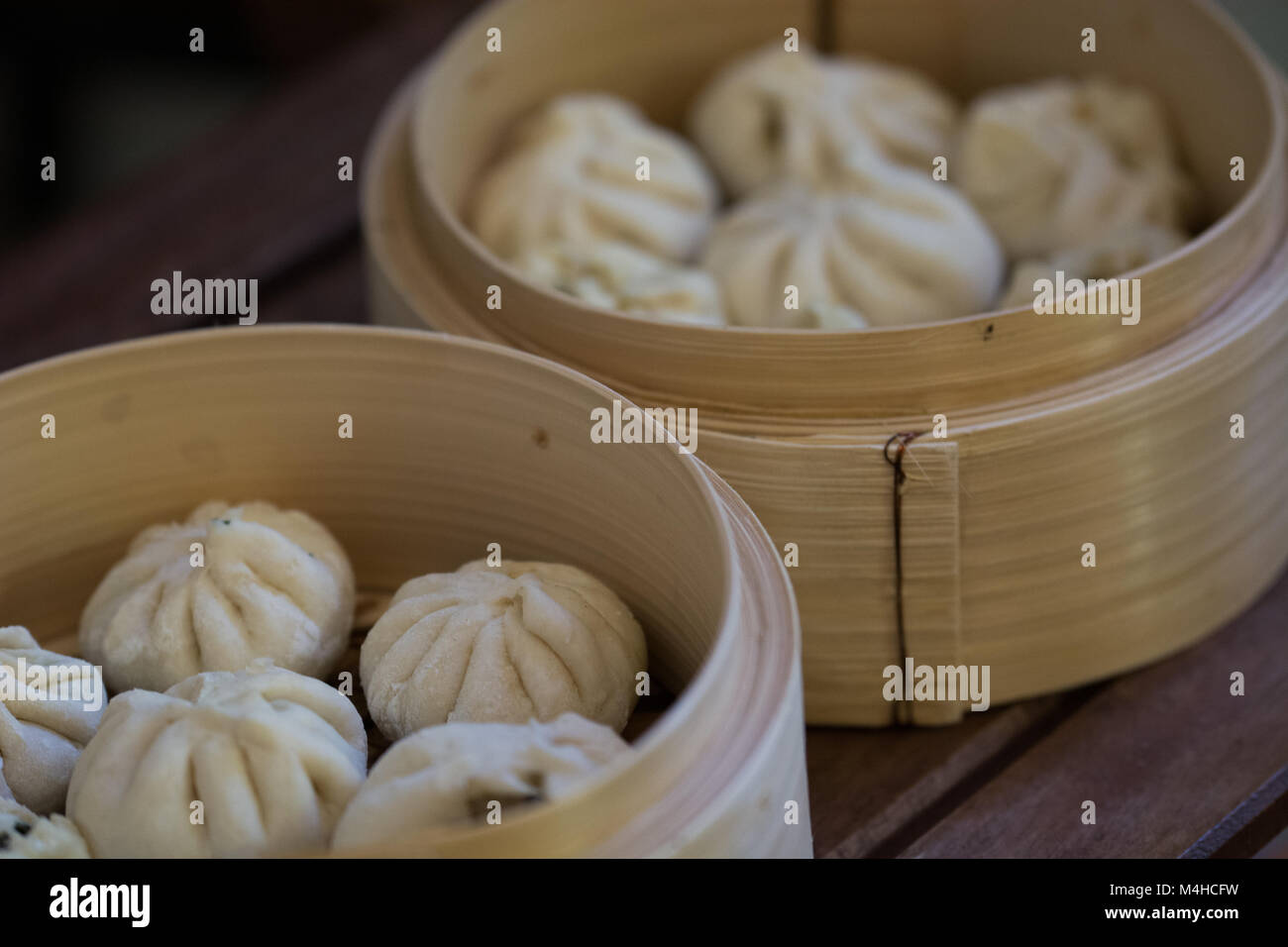 Chinesische Knödel (baozi) in einem traditionellen Holz- Bambus Warenkorb Dampfgaren Stockfoto