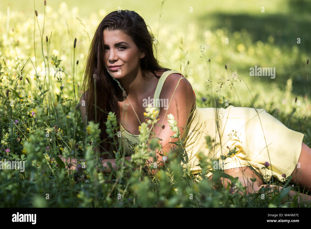 Junge Frau im Sommerkleid liegen auf der Wiese Stockfoto