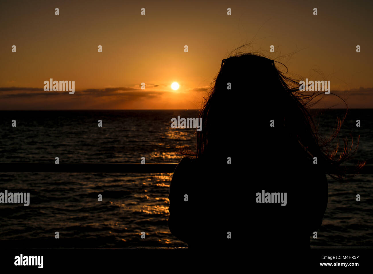 Frau mit Blick auf den Sonnenuntergang am Meer auf einer Fähre Stockfoto