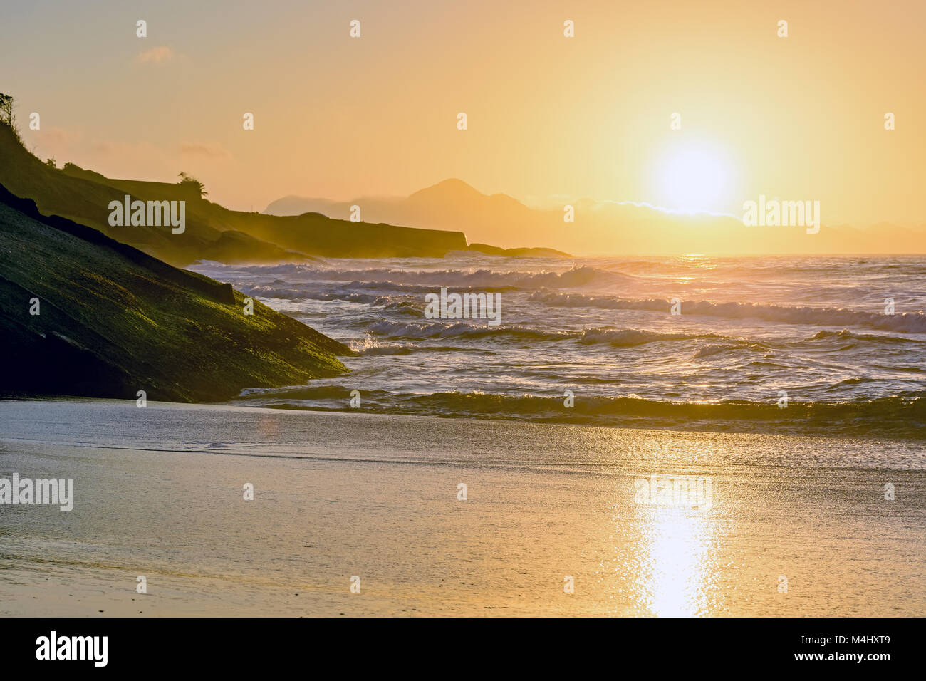 Wasser, Steine und Sand bei Sonnenaufgang Stockfoto