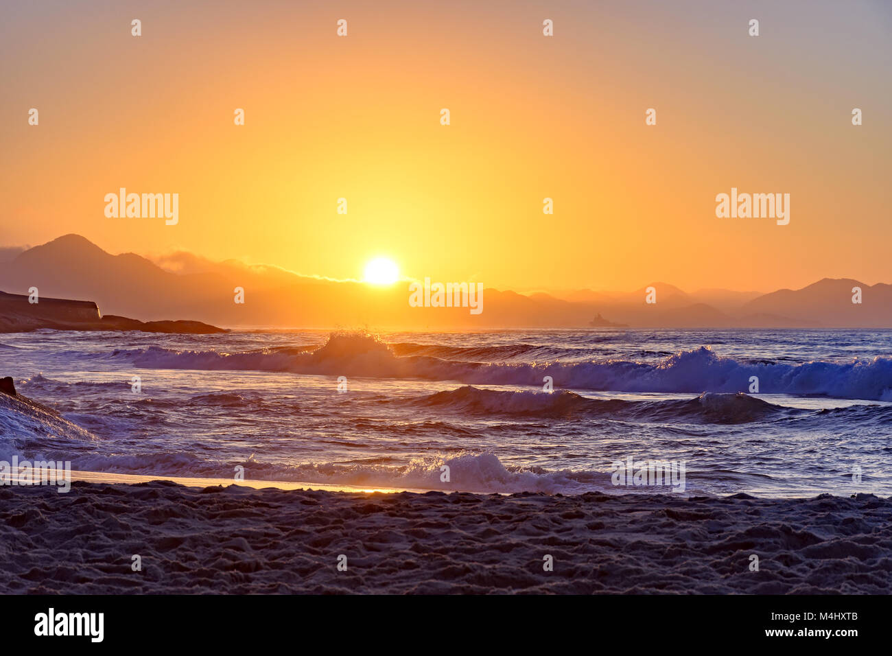 Wasser, Steine und Sand bei Sonnenaufgang Stockfoto