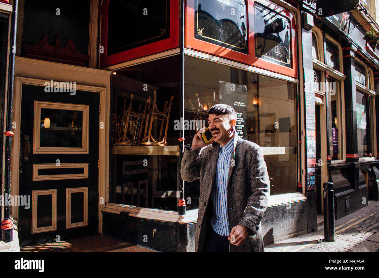 Unternehmer ist zu Fuß in der Stadt zu arbeiten. Er ist Sprechen und Lachen auf dem Telefon wie er geht. Stockfoto