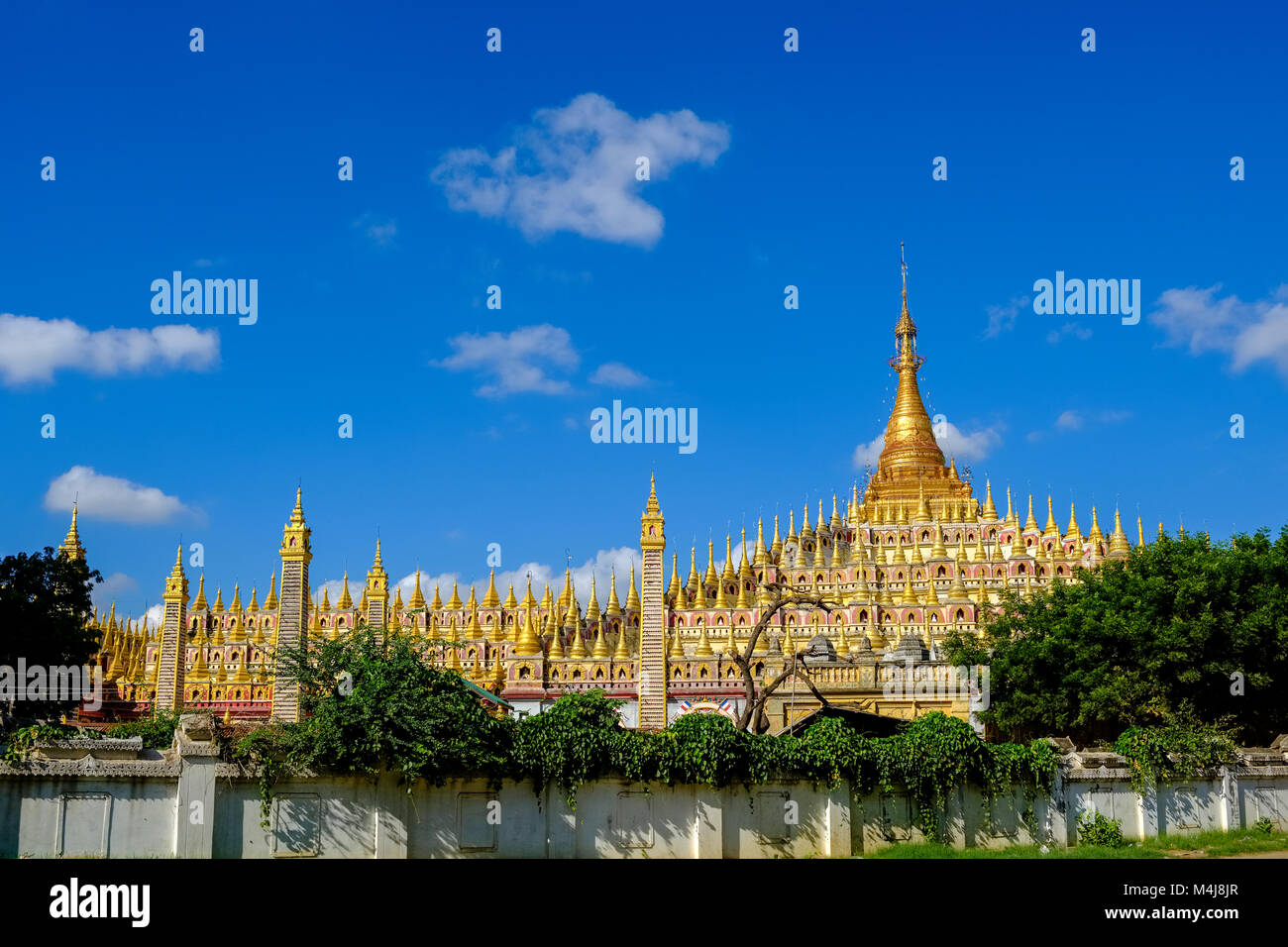 Blick auf die thanboddhay Pagode, der von einer Mauer und Bäume umgeben Stockfoto