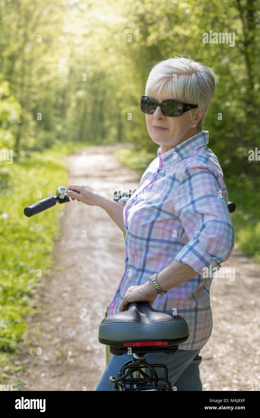 Eine ältere Frau mit kurzen grauen Haaren und Fahrrad Stockfoto