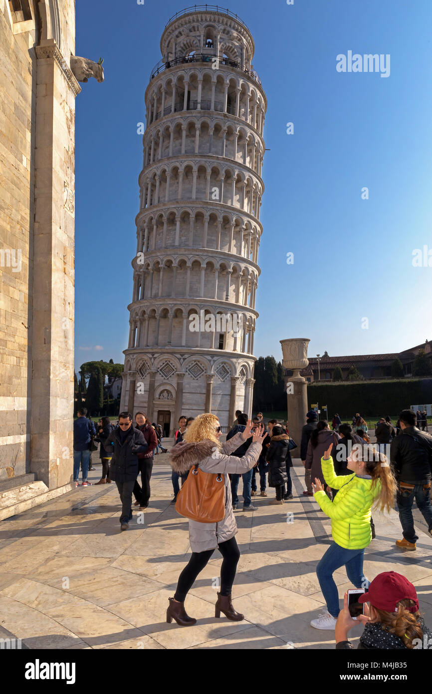 Pisa, Italien - 11. Februar 2018: Mutter und Tochter für ein Bild mit dem berühmten Turm von Pisa im Hintergrund darstellen, in einem überfüllten Piazza dei Miracoli Stockfoto