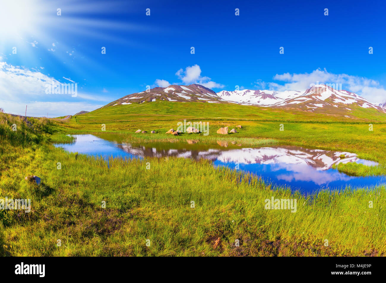 Summer Island. Blauer See Wasser reflektiert Schnee Hügel Stockfoto