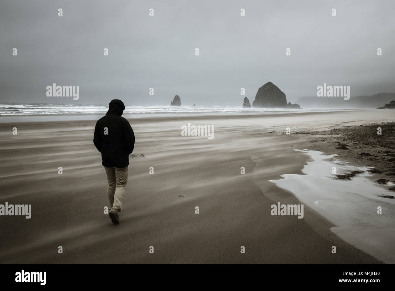 Einsamer Mann gegen die starken Böen stürmischer Cannon Beach. Stockfoto