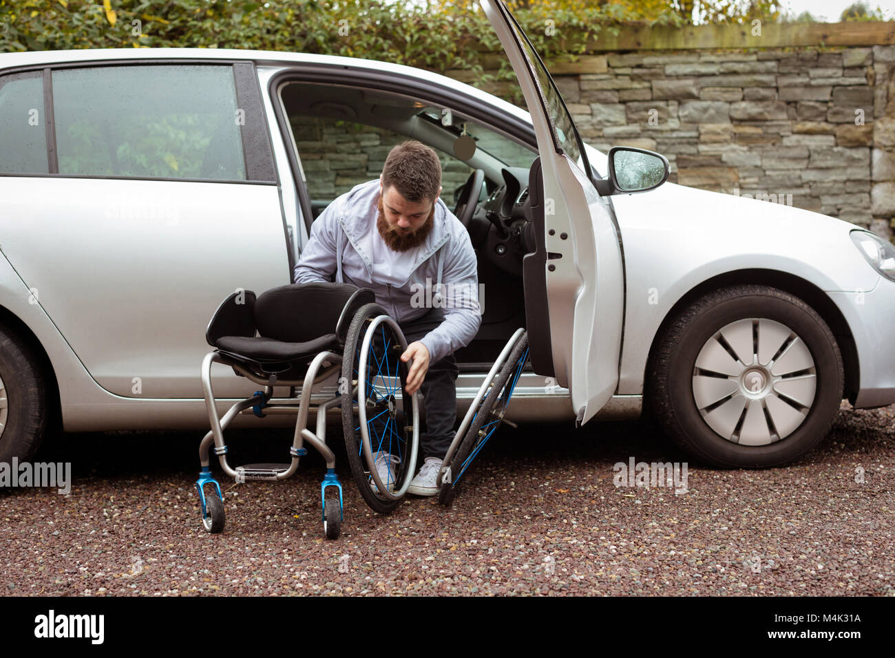 Behinderte Menschen im Rollstuhl halten und Aussteigen aus einem Auto Stockfoto