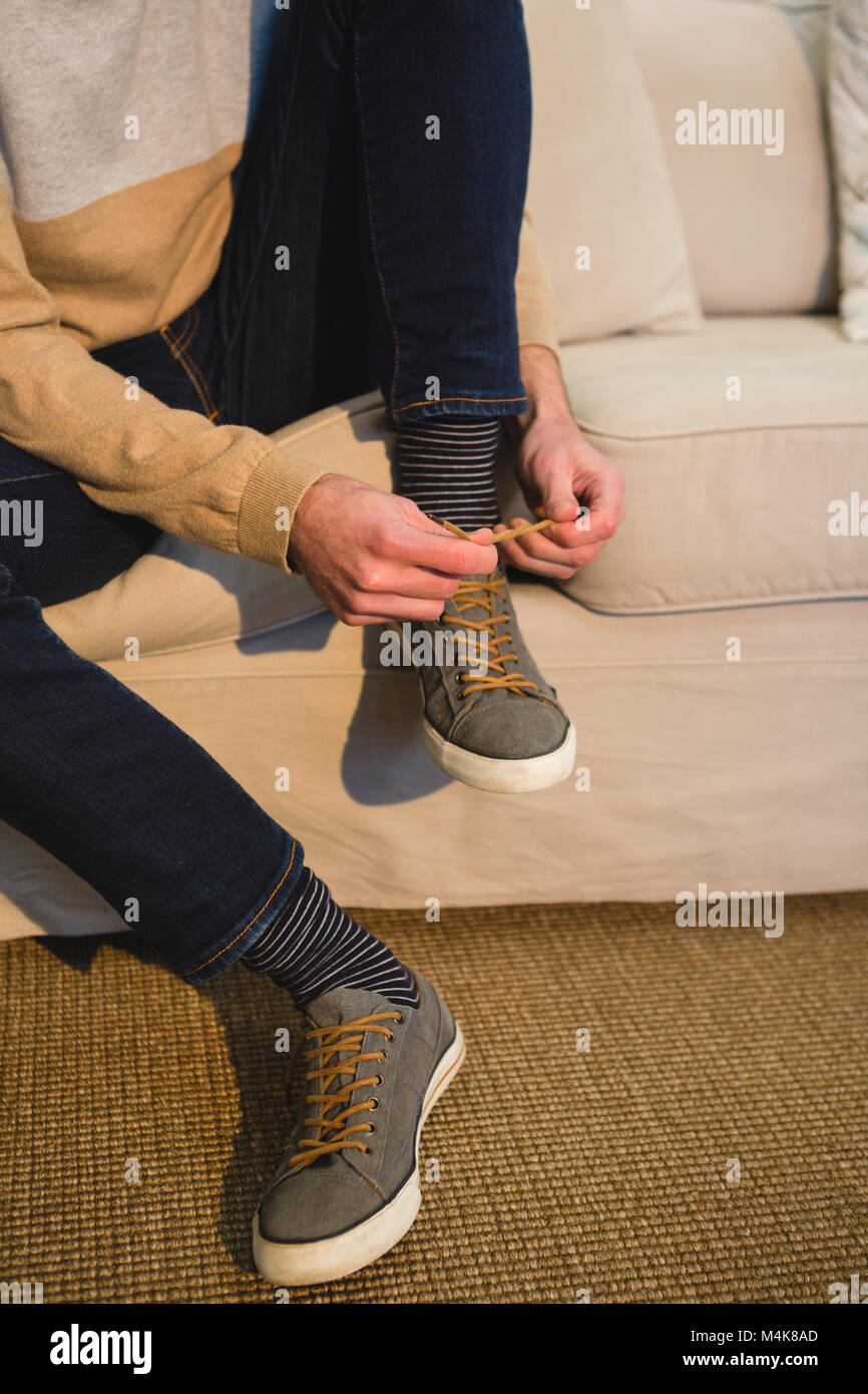 Mann binden Schnürsenkel in Wohnzimmer zu Hause Stockfoto