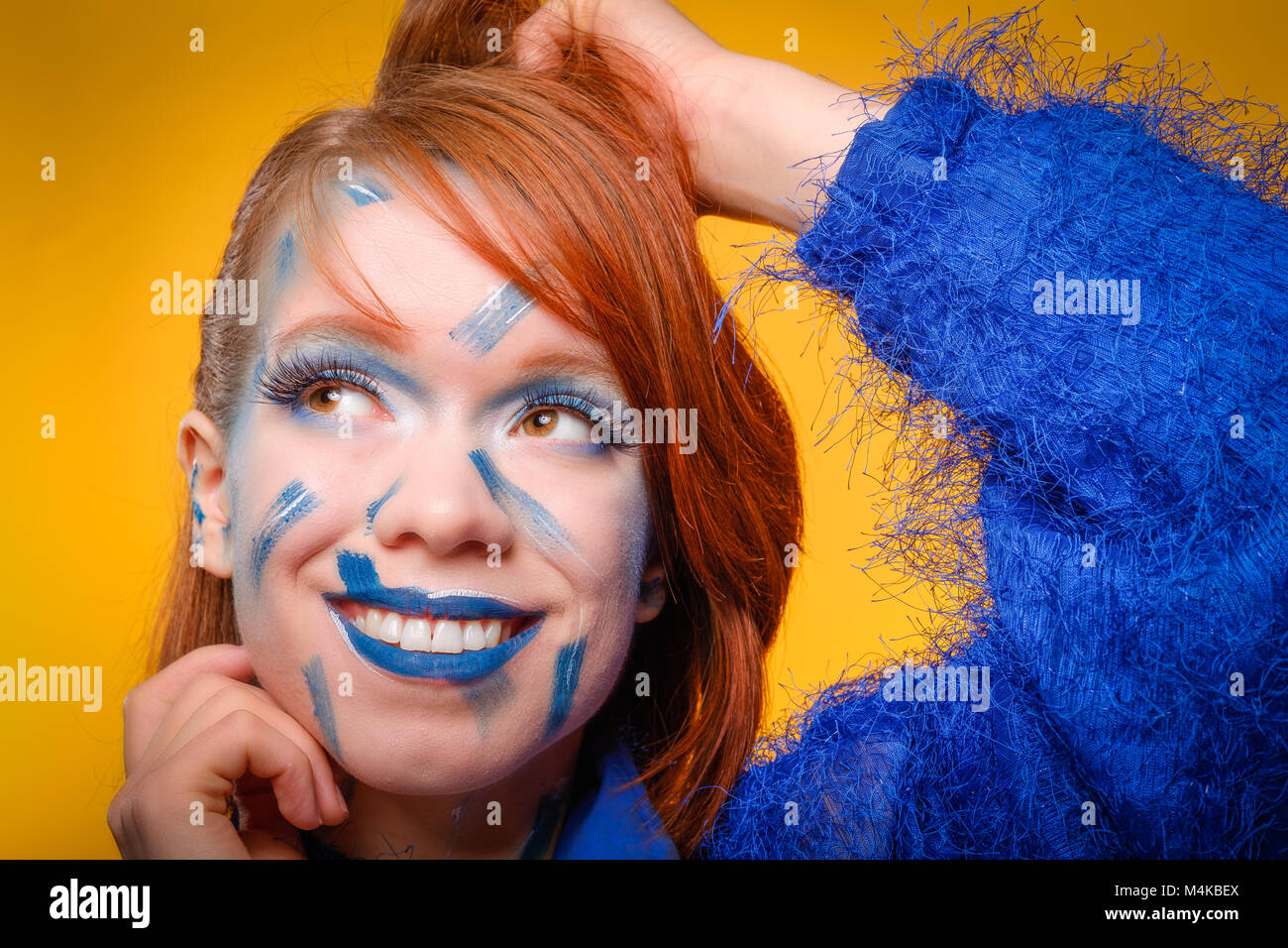 Glücklich, hübsche, rothaarige junge Frau trägt ein fuzzy Steckbrücke blau, mit verrücktem Blau Make-up, lächelnd © Jeremy Graham-Cumming Stockfoto