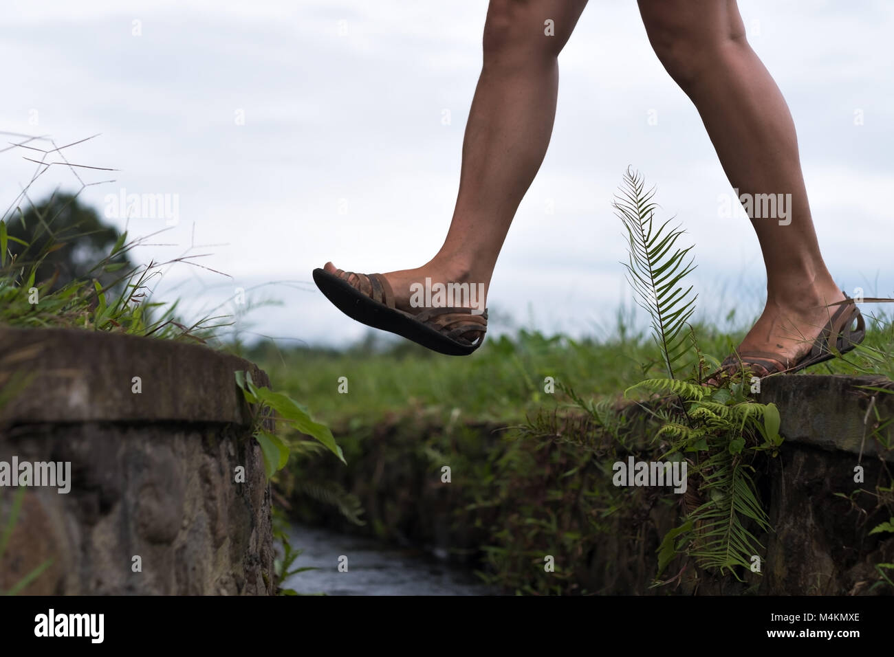 Kaukasische Frau Schritt über den Wassergraben. Se hat einen aktiven Urlaub in Asien und gilt für einen Spaziergang Stockfoto