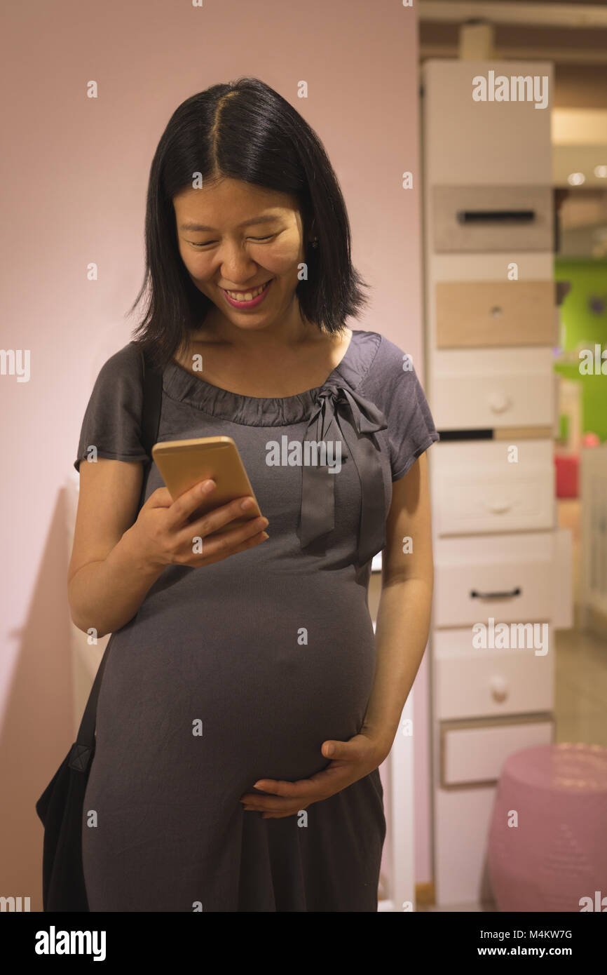 Schwangere Frau ihren Bauch berühren, während mit Handy Stockfoto