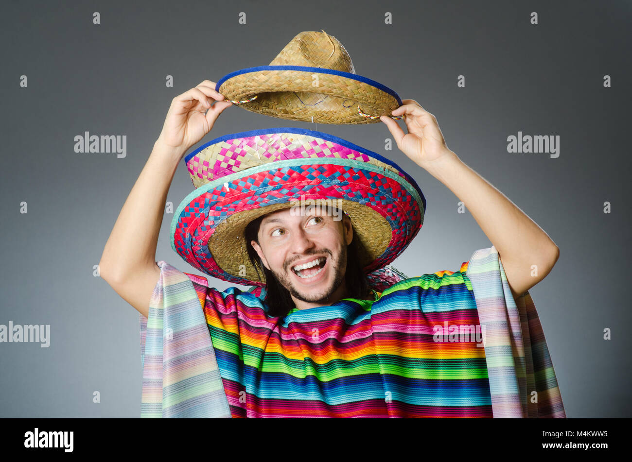 Mann in einem lebendigen mexikanischen Poncho grauen Hintergrund isoliert Stockfoto