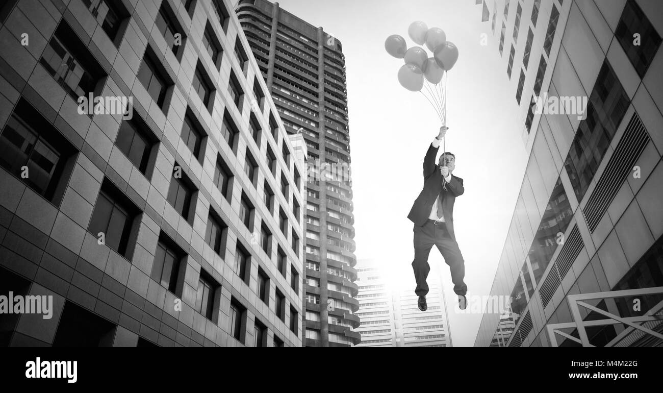 Geschäftsmann floating mit Ballons über surreale Stadt Gebäude Perspektive Stockfoto