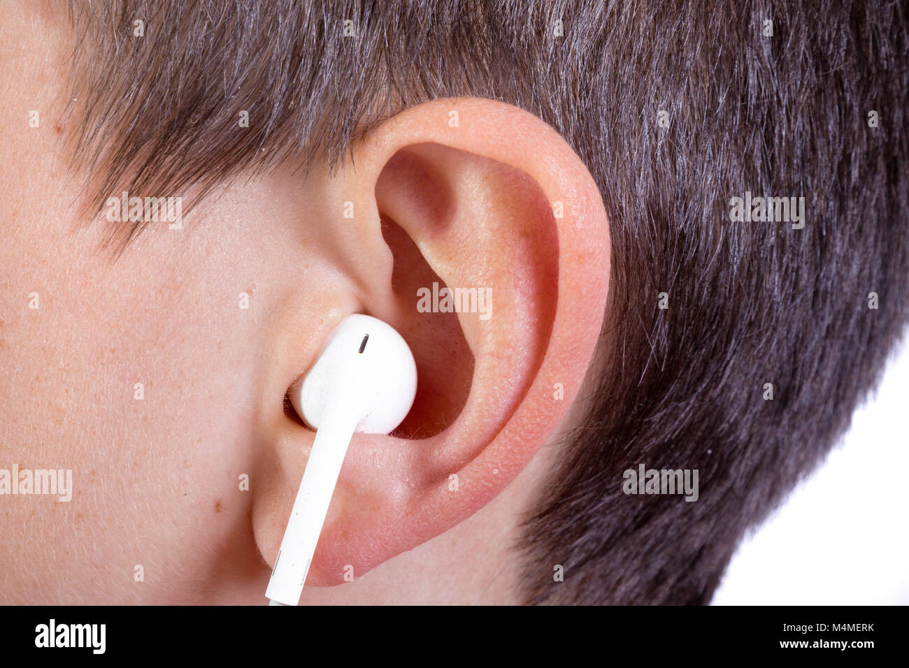 Der jungen kaukasischen Teenager Jungen linken Ohr mit einem Ohrhörer Kopfhörer Stockfoto