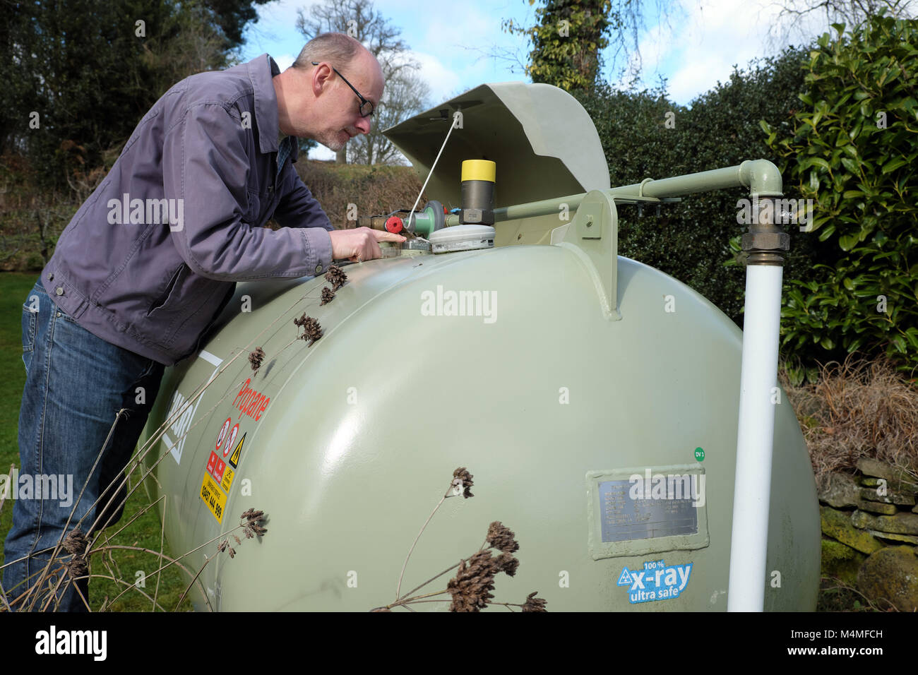 Calor gas männlichen Kunden lesen der Kapazität Meterspur in einem ländlichen UK Einstellung Stockfoto