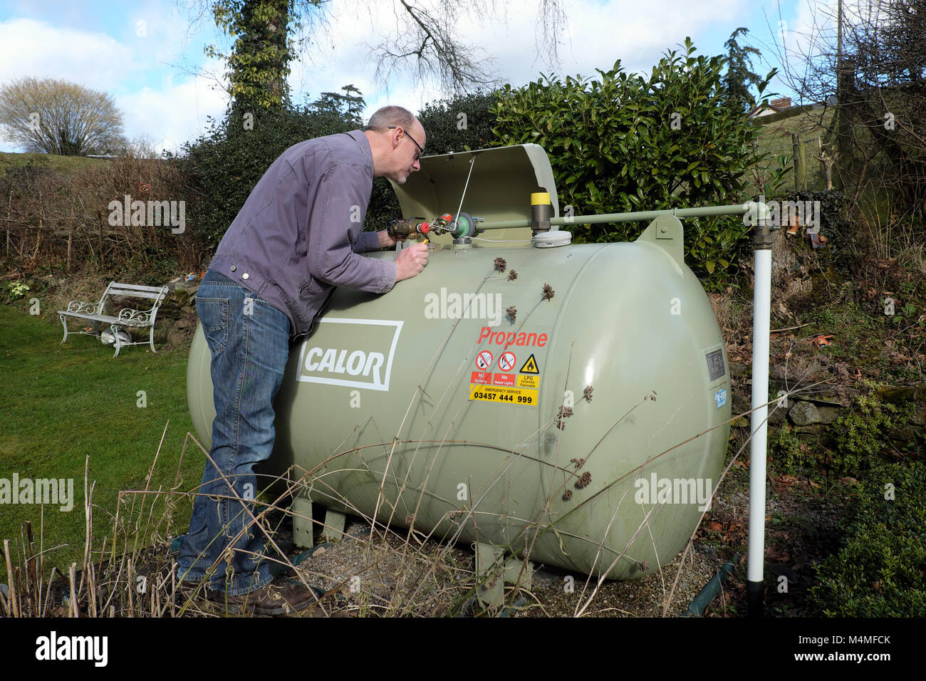 Calor gas männlichen Kunden lesen der Kapazität Meterspur in einem ländlichen UK Einstellung Stockfoto