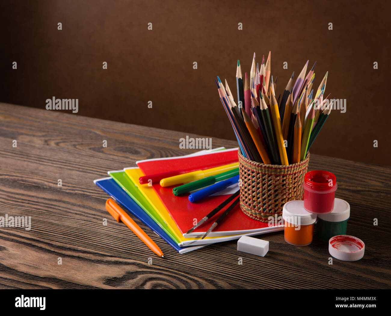 Bleistifte, Farben und Pinsel auf Holztisch. Stockfoto