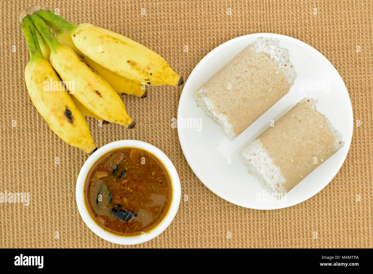 Platte von Puttu (populäre Südindische Frühstück Teller) mit Kichererbsen Curry und Bananen auf eine Jute mat. Stockfoto Platte von Puttu (populäre Südindische Frühstück Teller) mit Kichererbsen Curry und Bananen auf eine Jute mat. Stockfoto