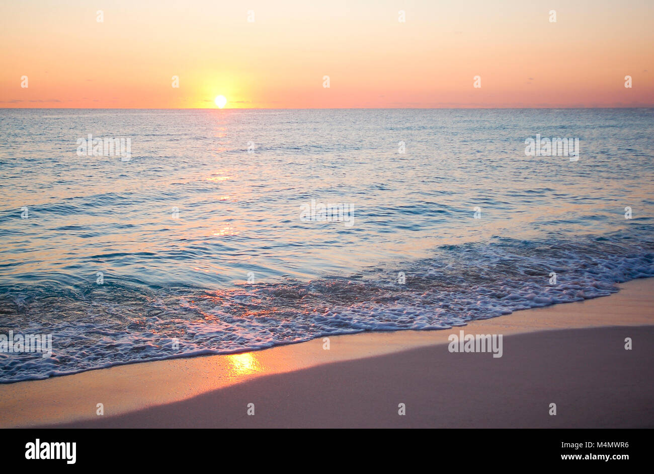 Schöner Strand Sonnenaufgang mit ruhigen Wellen Stockfoto