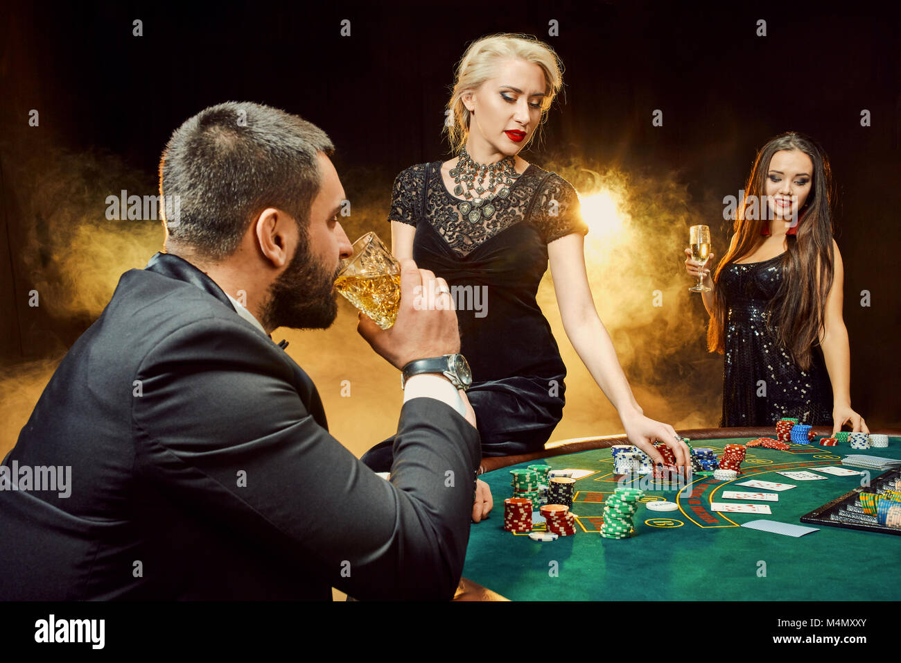 gruppe-von-jungen-reiche-leute-ist-poker-spielen-im-casino-mann-in-anzug-und-zwei-junge-frauen-in-schwarzen-kleidern-rauch-casino-poker-m4mxxy.jpg