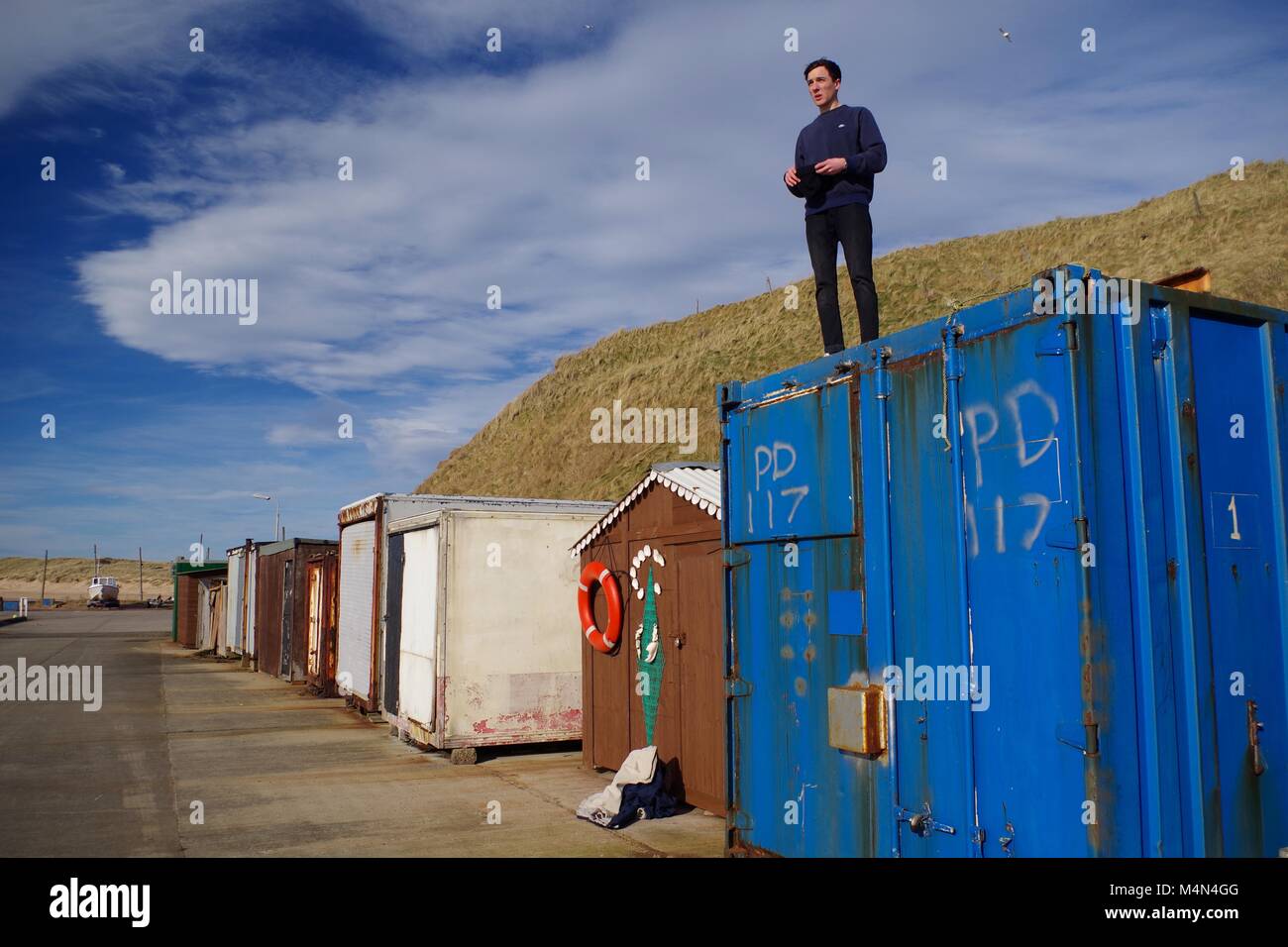 Junge Mann auf einem alten Versandverpackung an Cruden Bay Harbour, Aberdeenshire, Schottland, Großbritannien. Winter, 2018. Stockfoto