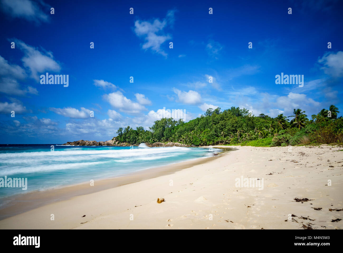Schönes Paradies Tropischer Strand mit Palmen, Granitfelsen, weißer Sand, blauer Himmel und türkisfarbenem Wasser, Polizei Bay, Mahé, Seychellen Stockfoto