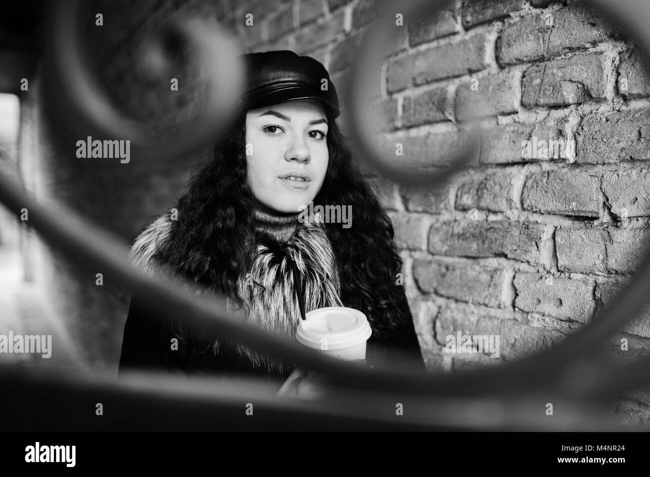 Curly mexikanische Mädchen in Leder und Plastik Tasse Kaffee zur Hand gehen an Straßen der Stadt. Stockfoto