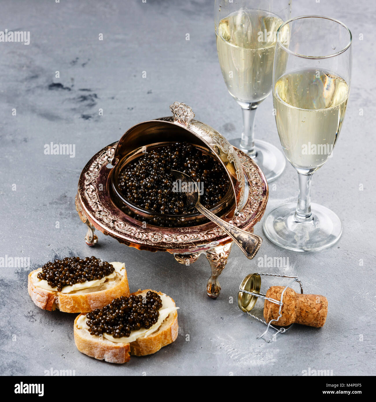 Schwarzer Kaviar in silberne Schale, Sandwiches und Champagner auf grauem Beton Hintergrund Stockfoto
