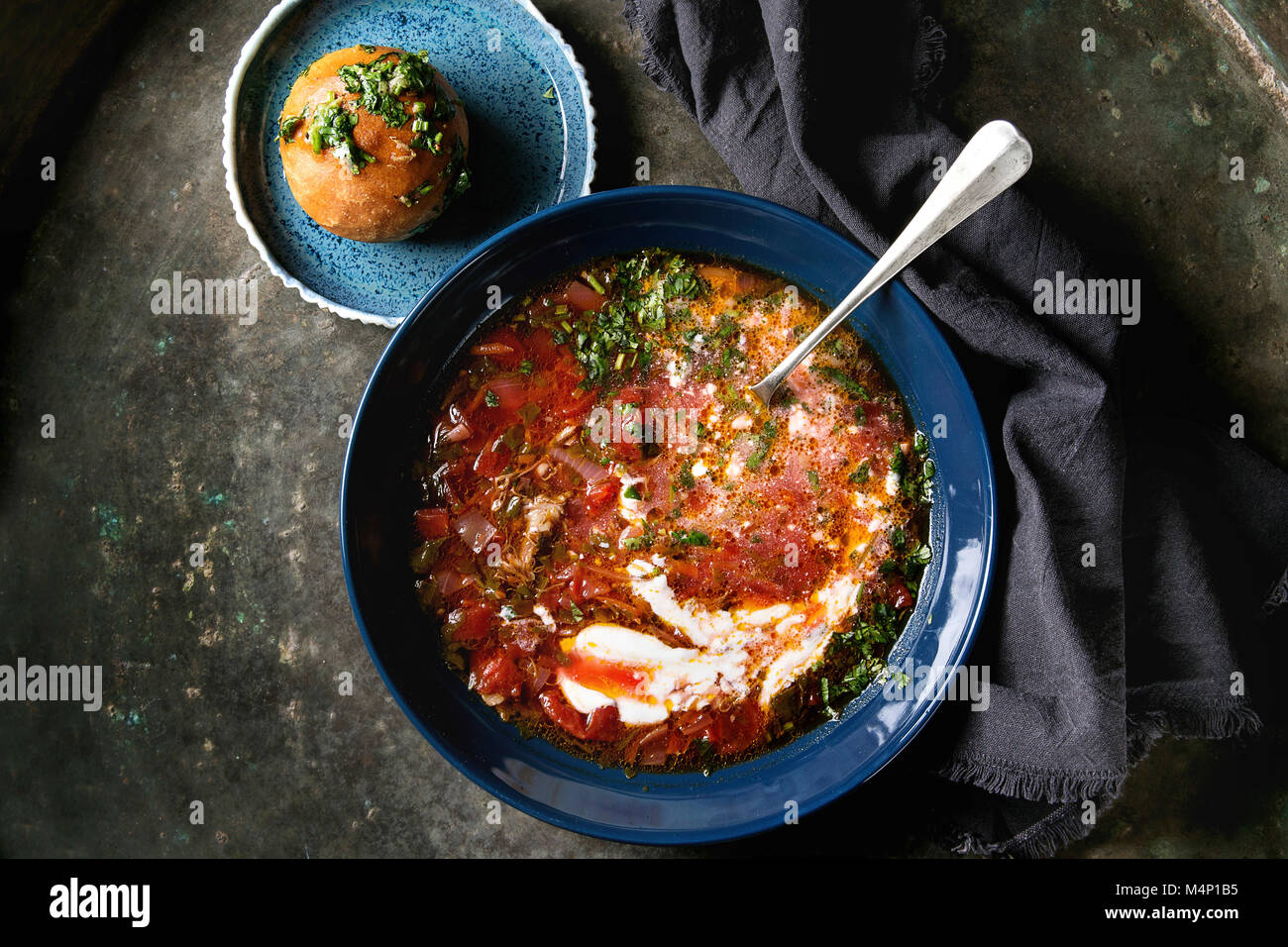 Platte der traditionellen Rote-Bete-Suppe Borschtsch mit saurer Sahne, Löffel und frischem Koriander serviert mit Knoblauch Brötchen pampushka mit schwarzem Textil napki Stockfoto