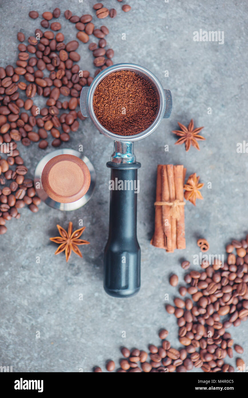 Portafilter mit gemahlenen Kaffee, Sabotage, Zimt und Bohnen auf einem Marmor Hintergrund. Kaffee mit kopieren. Stockfoto