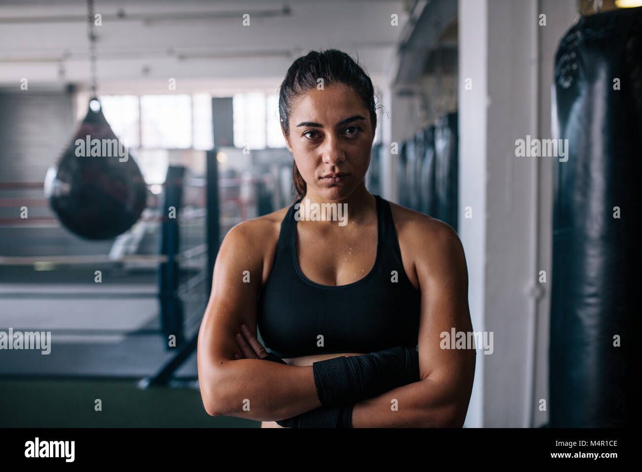 Nahaufnahme eines weiblichen Boxer in einem Boxen Studio stehen und Ihre Hände gefaltet. Frau, die in einem Zentrum mit boxtraining Boxsäcke und Bo Stockfoto