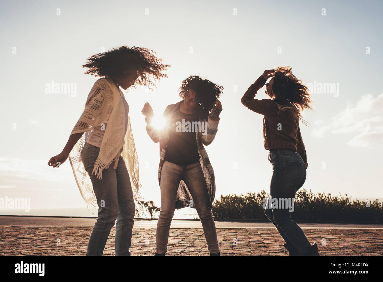 Weibliche Freunde tanzen und Spaß entlang der Straße keine einen sonnigen Tag. Drei junge Frauen genießen Sie auf Ihrer Reise. Freundinnen in den Urlaub genießen. Stockfoto