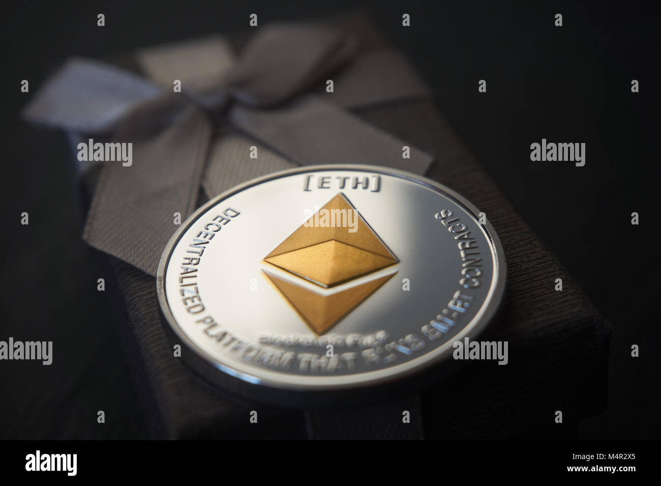 Silber Astraleums Münze liegen auf dem auf dem grauen Geschenkbox, grauen Stein Hintergrund. Cryptocurrency Geschenk Konzept, selektive konzentrieren. Stockfoto