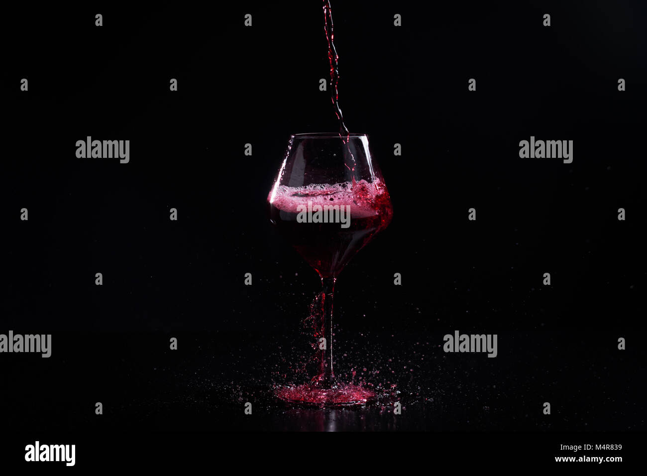 Gießen Rotwein in ein Glas Wein mit schwarzem Hintergrund Stockfoto