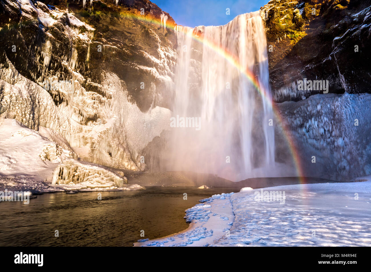 Skogafoss Wasserfall in Island hinter einer spektakulären Regenbogen Stockfoto