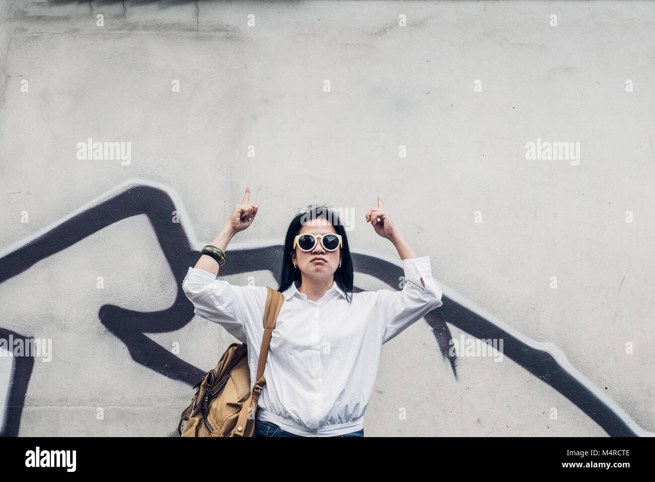 Asiatische hipster Frau tragen Sonnenbrillen stehen außen und oben an der alten Betonwand auf der Straße. Kopieren Sie Platz zum Hinzufügen von Text. Outdoor Reisen p Stockfoto