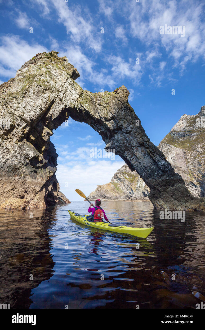 Kajakfahren auf dem Meer unter einem Natural Arch in der Nähe von Sturrall, Glencolmcille, County Donegal, Irland. Stockfoto