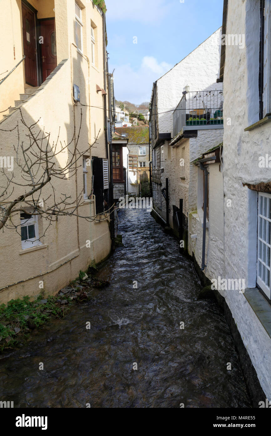 Schnell fließenden Fluss Pol in Polperro, Cornwall, UK läuft eng aneinanderliegende alte Häuser Stockfoto