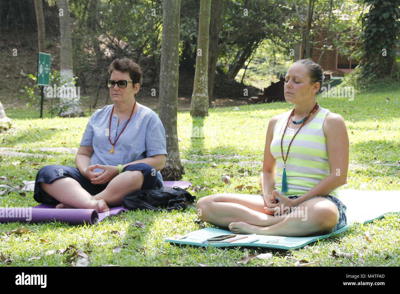 Zwei Frauen meditieren im Freien auf einer Wiese an einem Yoga Retreat in Indien Stockfoto