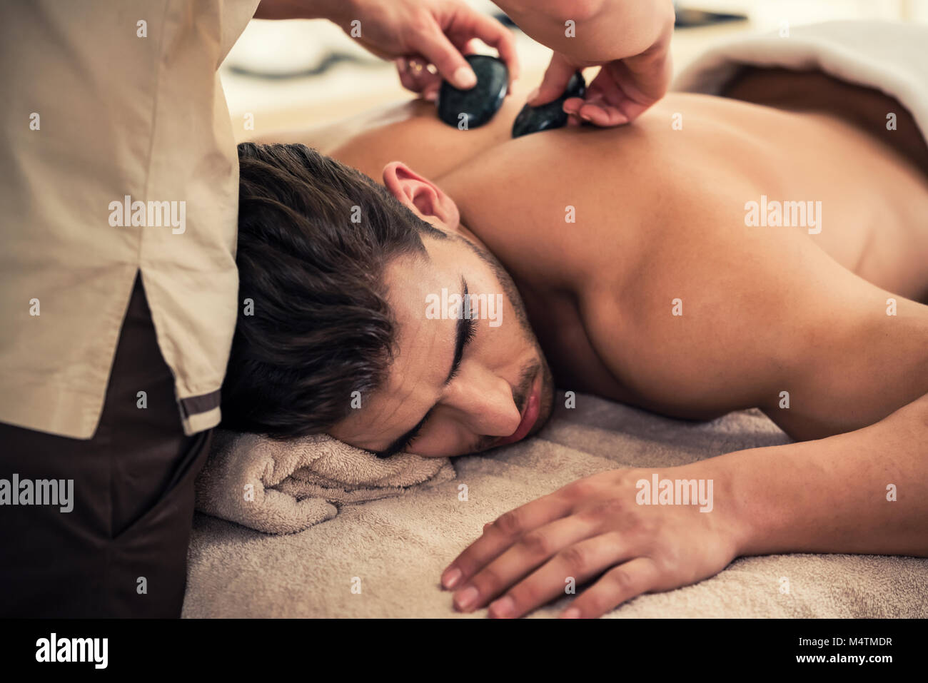 Man entspannen unter den stimulierende Effekte eines traditionellen Hot Stone Massage Stockfoto