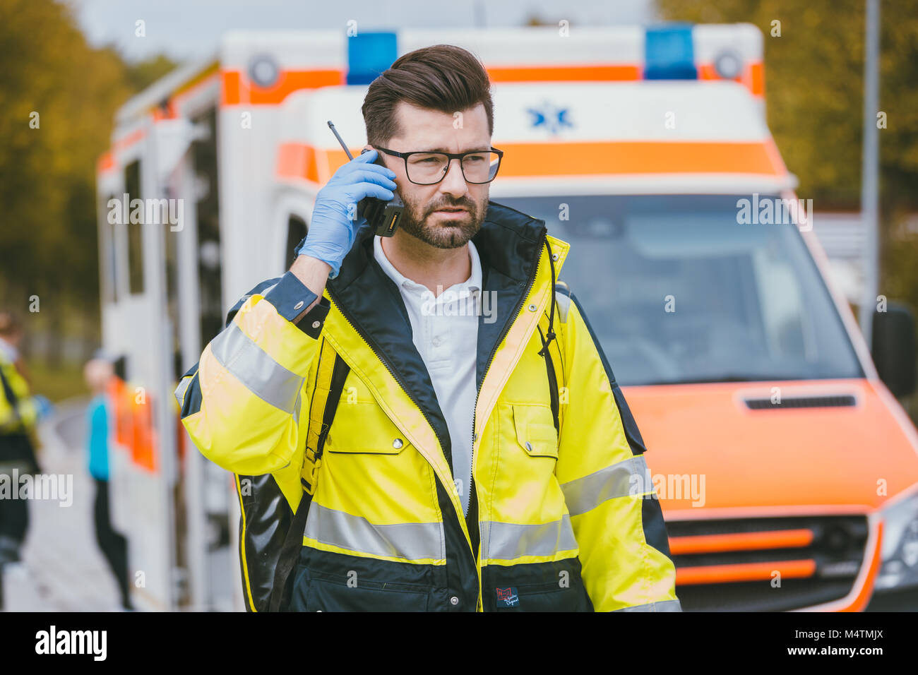 Medic im Gespräch mit der Zentrale über Radio vor der Ambulanz Stockfoto